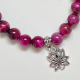 Close-up of magenta tiger eye beads jewelry with lotus charm