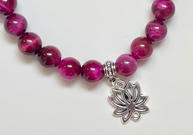 Close-up of magenta tiger eye beads jewelry with lotus charm