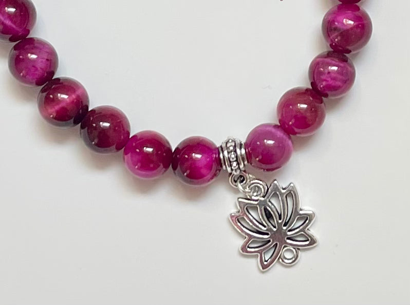 Close-up of magenta tiger eye beads jewelry with lotus charm